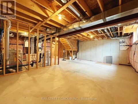 A spacious unfinished room with wooden beams and insulation on the walls.