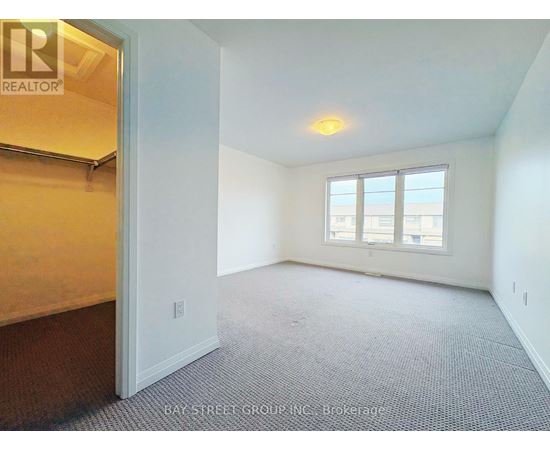 A room with a carpeted floor and a window with a view of the city.