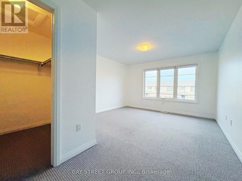 A room with a carpeted floor and a window with a view of the city.