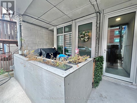 A concrete planter box with plants and a black umbrella on a patio.