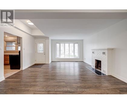 A spacious living room with a fireplace and hardwood floors.