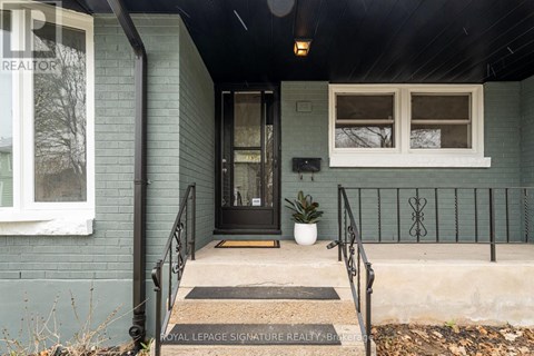 A house entrance with a black railing and a mat on the floor.