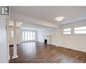 A spacious room with wooden floors and a fireplace.