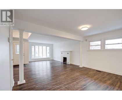A spacious room with wooden floors and a fireplace.