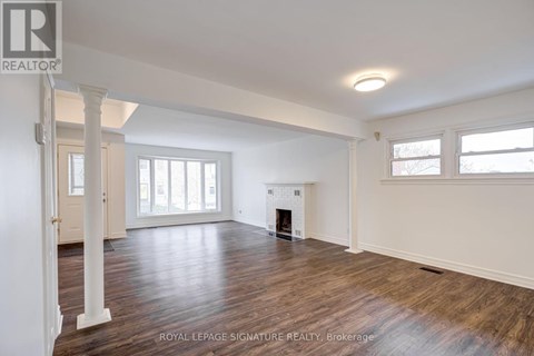 A spacious room with wooden floors and a fireplace.