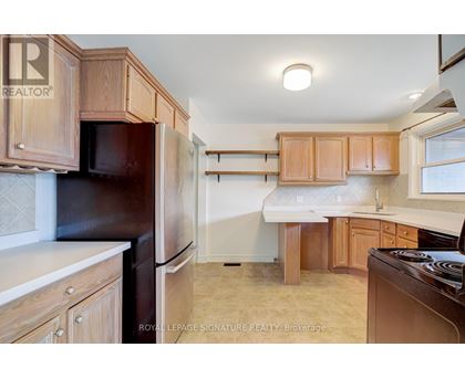 A kitchen with wooden cabinets and a black refrigerator.
