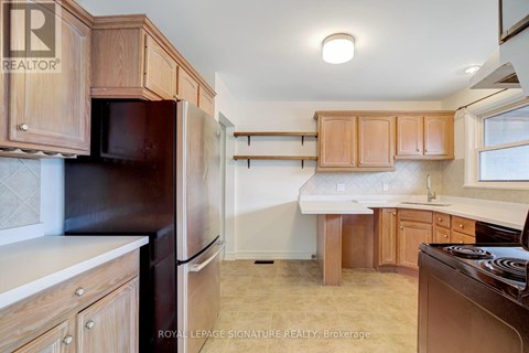 A kitchen with wooden cabinets and a black refrigerator.