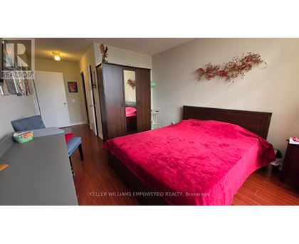 A bedroom with a red bedspread and a wooden bed.