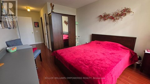 A bedroom with a red bedspread and a wooden bed.