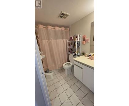 A bathroom with a pink shower curtain and white tiles.