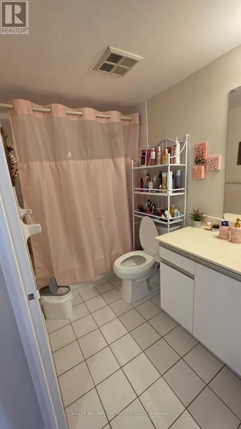 A bathroom with a pink shower curtain and white tiles.
