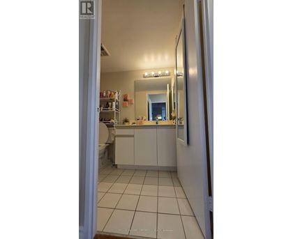 A bathroom with a white tiled floor and a mirror above a sink.