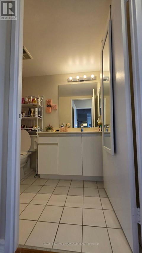 A bathroom with a white tiled floor and a mirror above a sink.