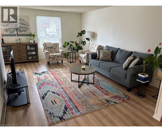 A living room with a grey couch and a rug with a face on it.