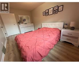 A bedroom with a pink bedspread and a white bed.