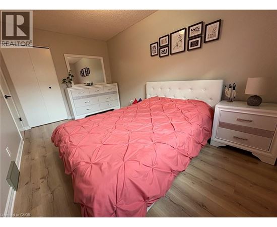 A bedroom with a pink bedspread and a white bed.