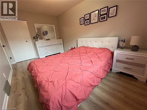 A bedroom with a pink bedspread and a white bed.