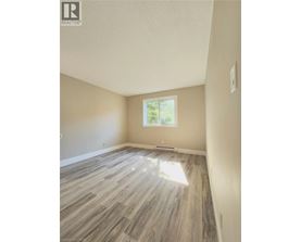 A room with light wood flooring and a window letting in sunlight.