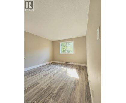 A room with light wood flooring and a window letting in sunlight.