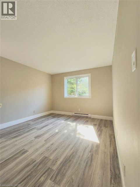 A room with light wood flooring and a window letting in sunlight.