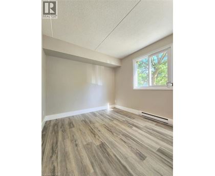 A room with wooden flooring and a window showing trees outside.
