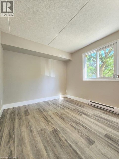 A room with wooden flooring and a window showing trees outside.
