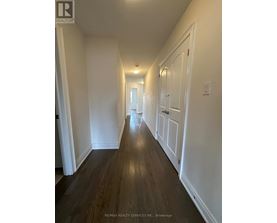 A long hallway with white walls and wood floors.