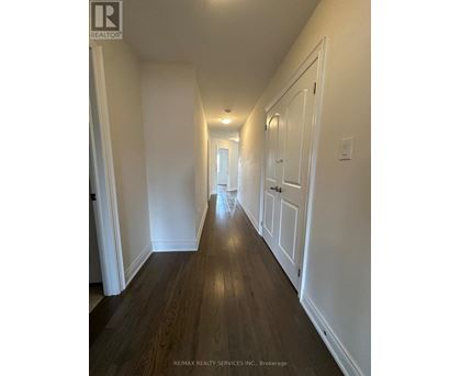 A long hallway with white walls and wood floors.