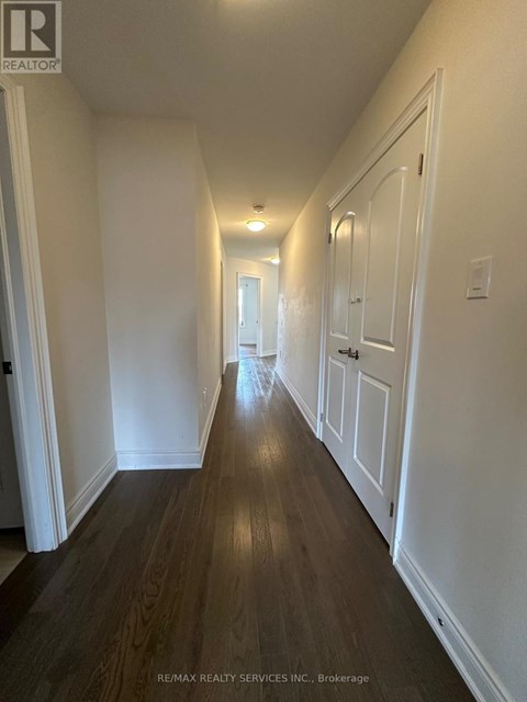 A long hallway with white walls and wood floors.