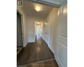 A hallway with wood floors and white walls.