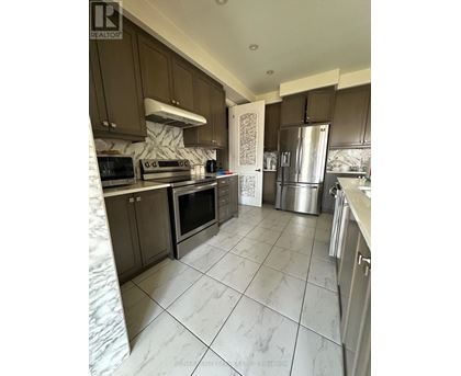 A kitchen with brown cabinets and a marble backsplash.