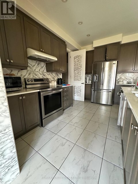 A kitchen with brown cabinets and a marble backsplash.