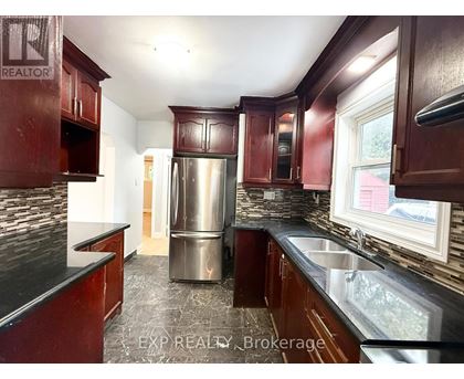 A kitchen with dark wood cabinets and a stainless steel refrigerator.