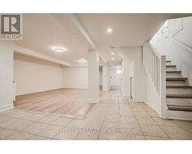 A spacious room with a staircase on the right side.