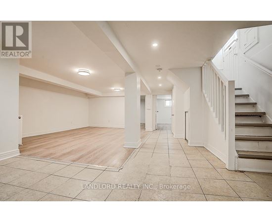 A spacious room with a staircase on the right side.