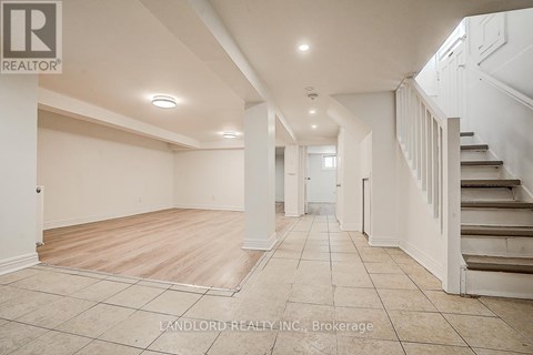 A spacious room with a staircase on the right side.