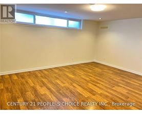 A room with wooden flooring and two windows.