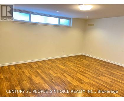 A room with wooden flooring and two windows.