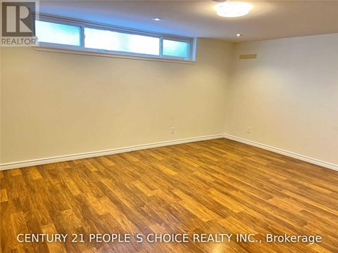 A room with wooden flooring and two windows.