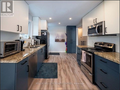A modern kitchen with dark blue cabinets and stainless steel appliances.