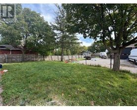 A backyard with a fence, a tree, and a grassy area.