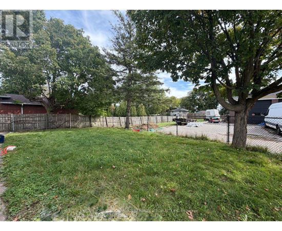 A backyard with a fence, a tree, and a grassy area.