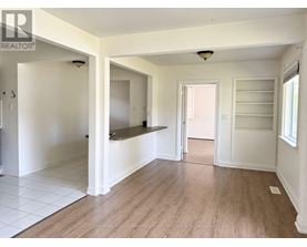 A spacious room with white walls and wooden flooring.