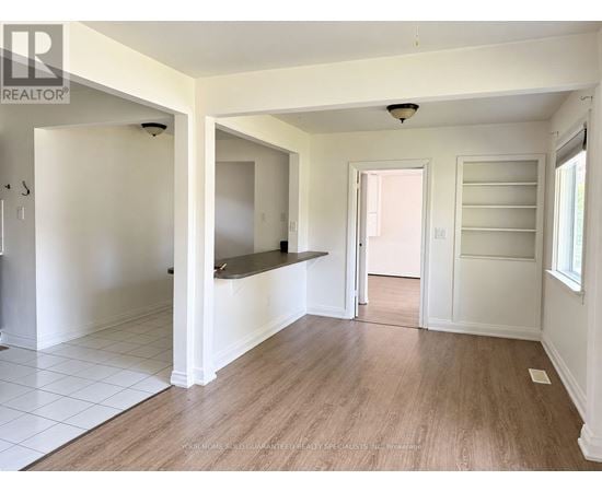 A spacious room with white walls and wooden flooring.