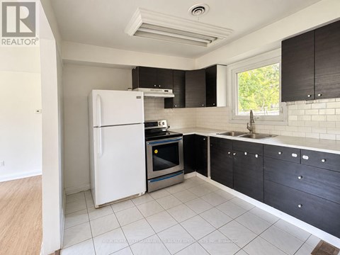 A kitchen with a white fridge, black cabinets, and a window.