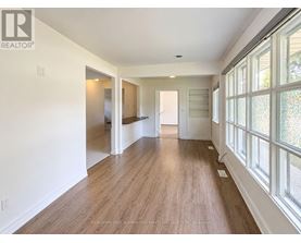 A long, empty hallway with wood floors and white walls.