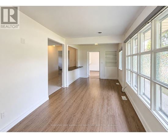 A long, empty hallway with wood floors and white walls.