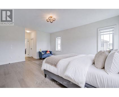 A bedroom with a large bed and a blue couch in the background.