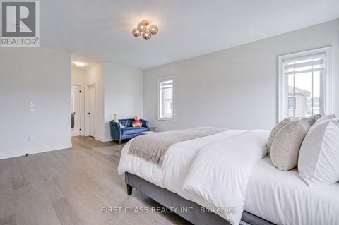 A bedroom with a large bed and a blue couch in the background.
