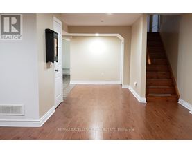 A hallway with wooden floors and a staircase on the right.